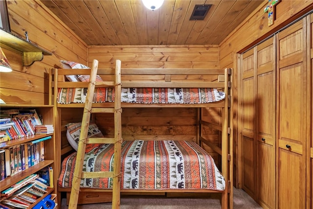 bedroom featuring a closet, carpet flooring, wooden walls, and wood ceiling