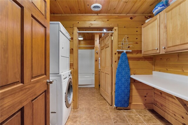 laundry room with stacked washer / dryer, wooden walls, light tile patterned flooring, and wood ceiling