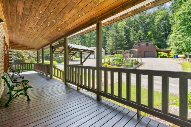 wooden terrace featuring a garage and an outbuilding