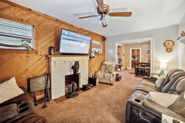 living room featuring carpet flooring, ceiling fan, wooden walls, and a brick fireplace