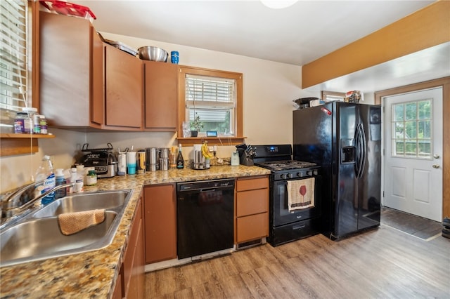 kitchen featuring sink, black appliances, and light hardwood / wood-style flooring