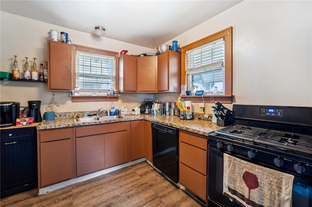 kitchen with sink, black appliances, light hardwood / wood-style flooring, and a healthy amount of sunlight