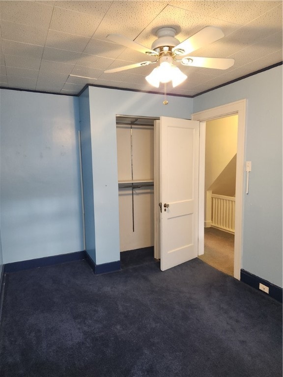 empty room featuring ceiling fan, a drop ceiling, and dark colored carpet