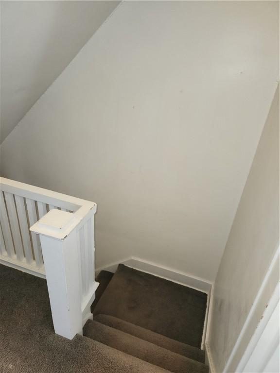 stairway featuring carpet floors and vaulted ceiling