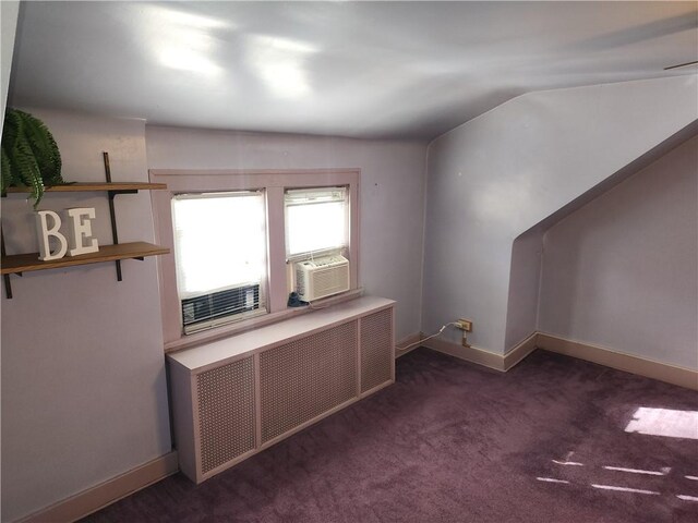 additional living space with dark carpet, lofted ceiling, radiator heating unit, and cooling unit