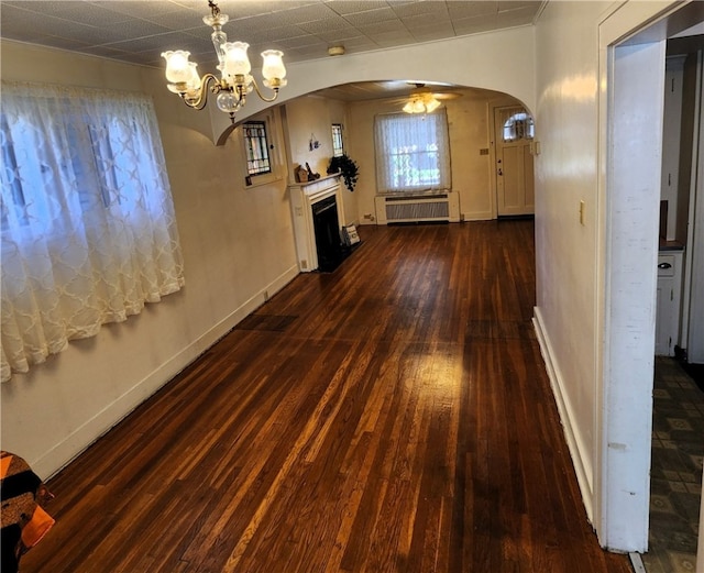 interior space with dark hardwood / wood-style flooring, radiator heating unit, and ceiling fan with notable chandelier