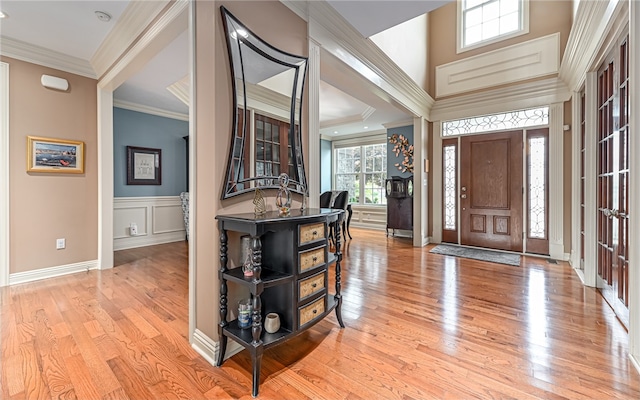 foyer with light wood-type flooring and crown molding