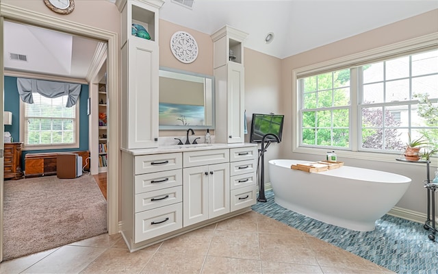 bathroom featuring a tub to relax in, a wealth of natural light, and vaulted ceiling