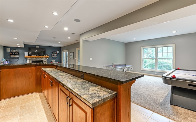 bar featuring a fireplace, dark stone countertops, and light carpet