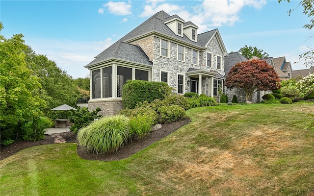 view of front facade with a sunroom and a front lawn