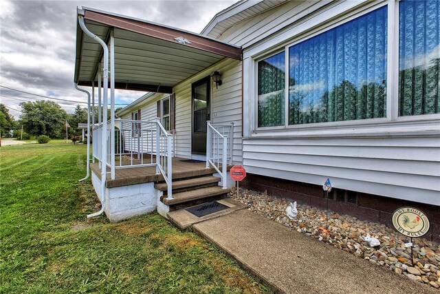 doorway to property with a porch and a yard