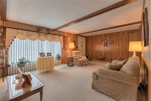 carpeted living room with a textured ceiling, wood walls, an inviting chandelier, and beamed ceiling