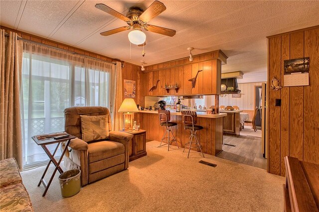 carpeted office featuring a textured ceiling, ceiling fan, and wood walls