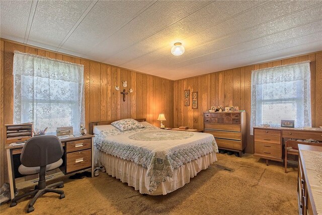 bedroom featuring wooden walls, a textured ceiling, and light carpet