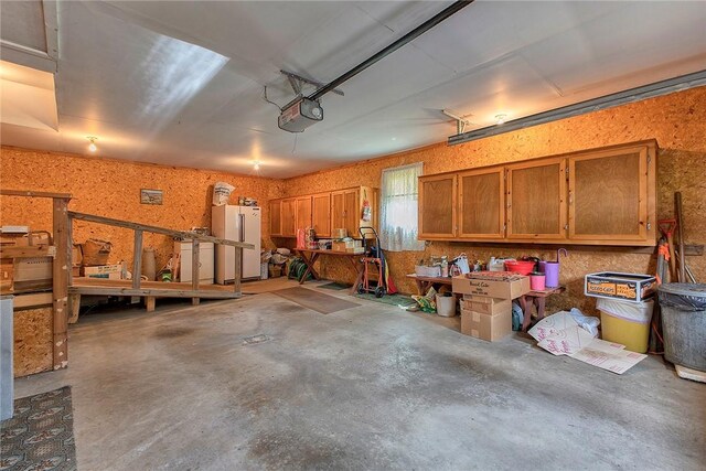 garage featuring a workshop area, a garage door opener, and white refrigerator