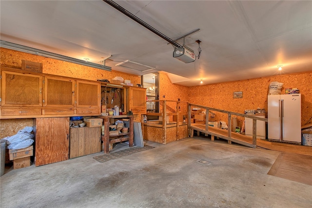 garage with a workshop area, a garage door opener, and white fridge