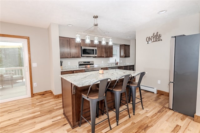 kitchen with light hardwood / wood-style flooring, baseboard heating, decorative light fixtures, a center island, and stainless steel appliances