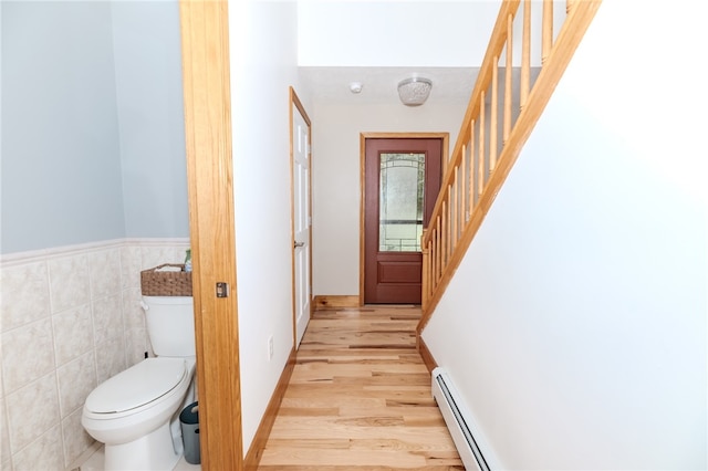 bathroom featuring tile walls, toilet, hardwood / wood-style flooring, and a baseboard radiator