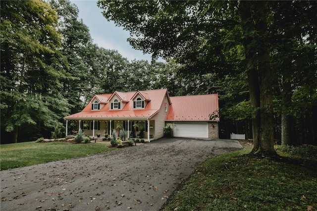 view of front of property featuring covered porch, a garage, and a front lawn