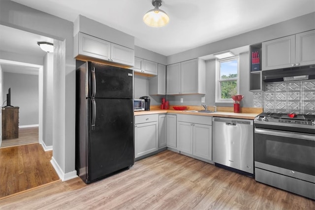 kitchen featuring sink, stainless steel appliances, decorative backsplash, and light wood-type flooring