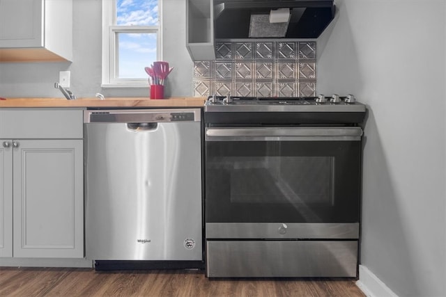 kitchen featuring hardwood / wood-style floors, dishwashing machine, white cabinets, range, and extractor fan