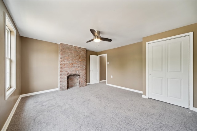 unfurnished living room with carpet floors, brick wall, ceiling fan, and a brick fireplace