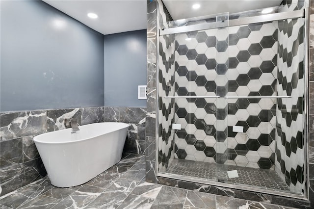 bathroom with tile walls, a shower with door, and tile patterned floors