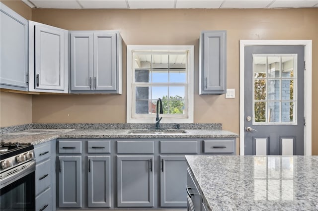 kitchen featuring sink, a paneled ceiling, a healthy amount of sunlight, and gas stove