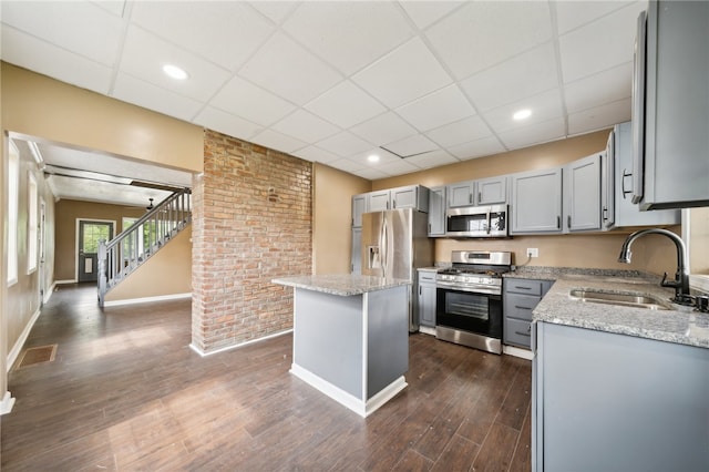 kitchen featuring sink, stainless steel appliances, a center island, and light stone counters