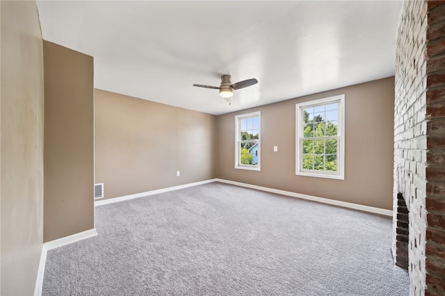 empty room with a fireplace, ceiling fan, and carpet