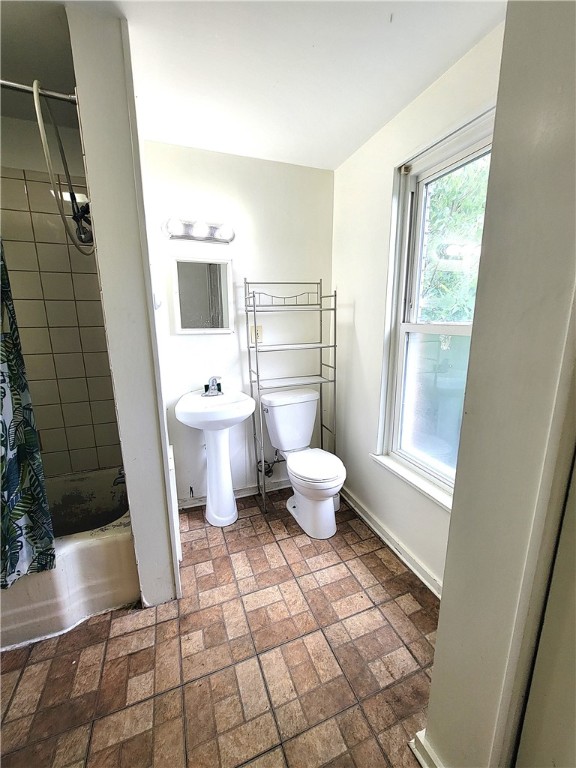 full bathroom with sink, shower / bath combination with curtain, a healthy amount of sunlight, and toilet