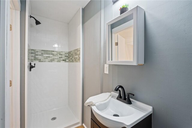 bathroom with vanity and tiled shower