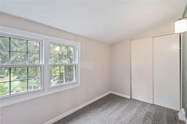 unfurnished bedroom with carpet flooring, vaulted ceiling, and a closet