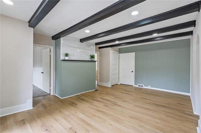 empty room featuring beam ceiling and light hardwood / wood-style flooring