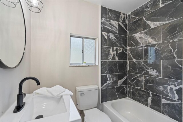 full bathroom featuring sink, tiled shower / bath combo, and toilet