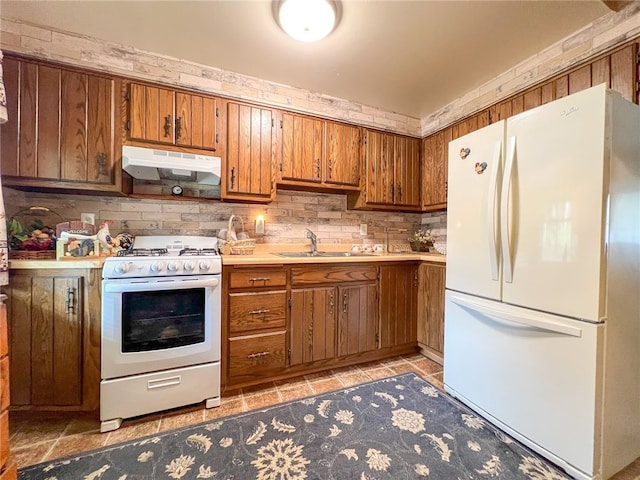 kitchen featuring wall chimney exhaust hood, tasteful backsplash, sink, light tile patterned floors, and white appliances