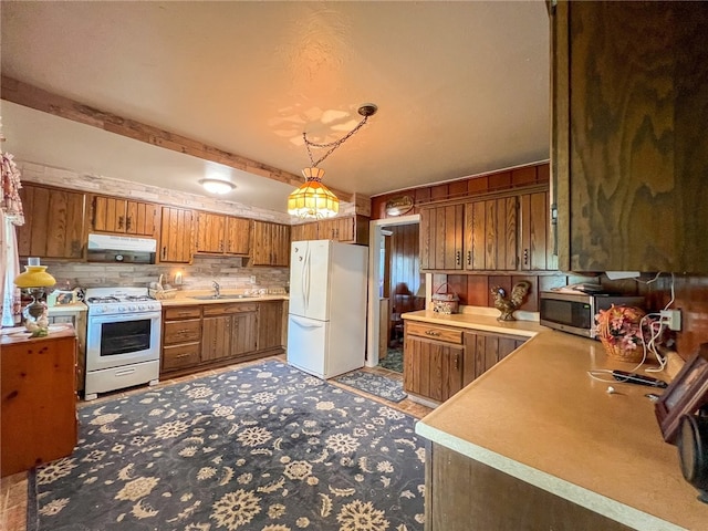 kitchen with sink, decorative light fixtures, backsplash, and white appliances