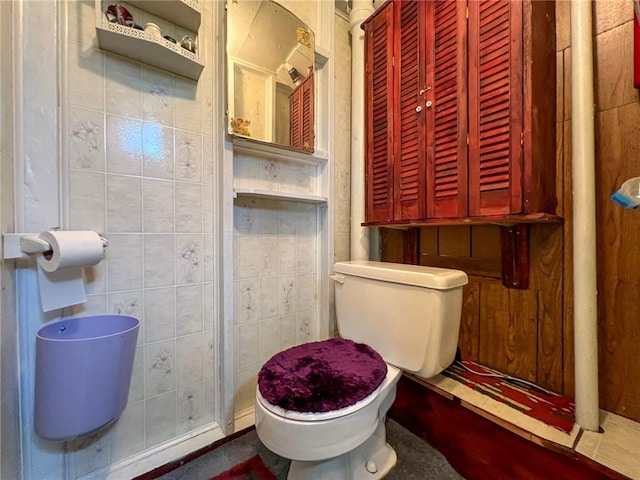 bathroom featuring tile walls, tile patterned flooring, and toilet