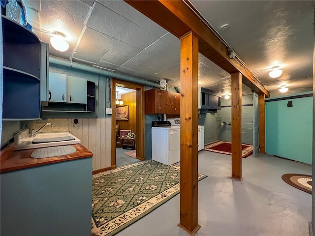 basement featuring sink, washer and dryer, and wood walls