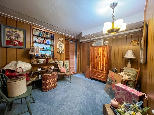 living area featuring wooden walls, an inviting chandelier, and carpet