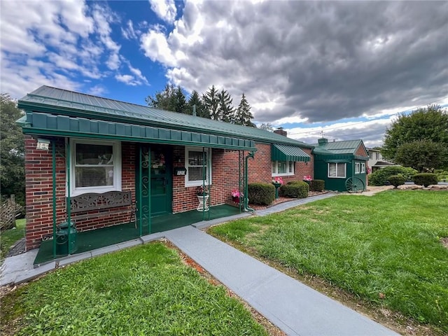 single story home featuring a front yard, brick siding, and metal roof