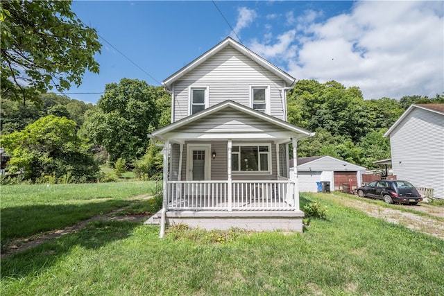 view of front facade featuring a porch, an outbuilding, a garage, and a front yard