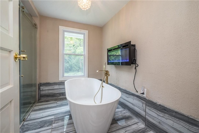 full bathroom with a soaking tub and a textured wall