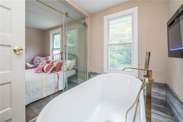 bedroom with access to outside, multiple windows, and wood finished floors