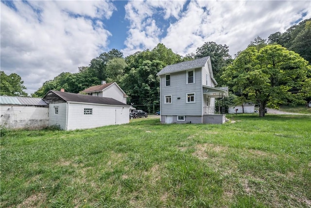 back of property featuring a yard and an outdoor structure