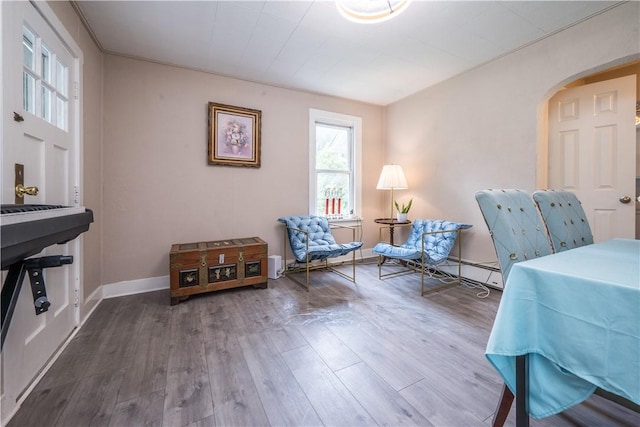 living area featuring baseboards, arched walkways, and wood finished floors