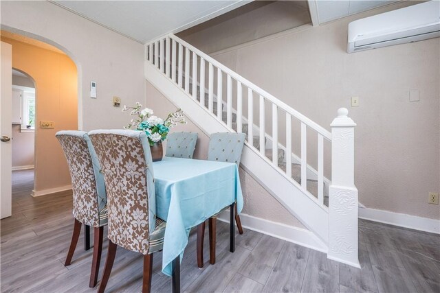 dining space featuring hardwood / wood-style floors and a wall mounted air conditioner