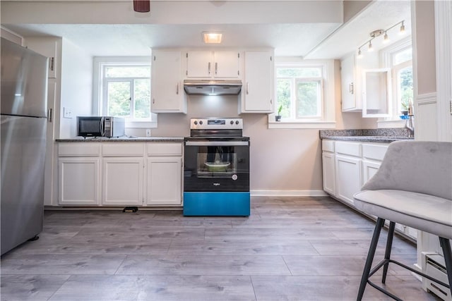 kitchen with light wood finished floors, range with electric cooktop, freestanding refrigerator, a healthy amount of sunlight, and under cabinet range hood