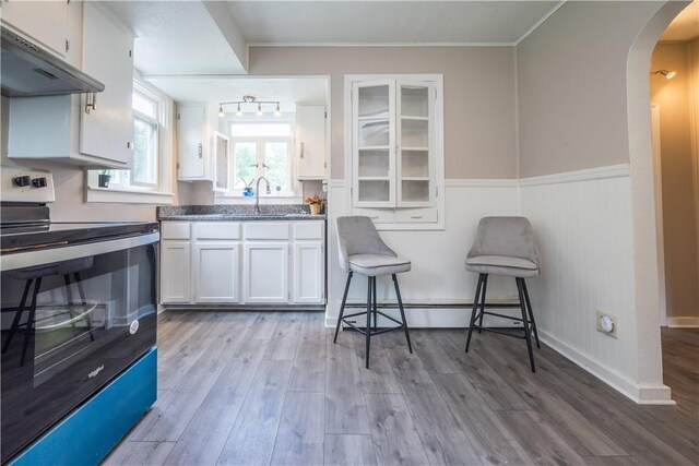 kitchen featuring white cabinets, track lighting, electric range, and wood-type flooring