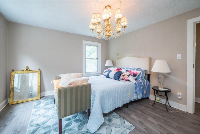 bedroom with hardwood / wood-style flooring, a textured ceiling, and a chandelier